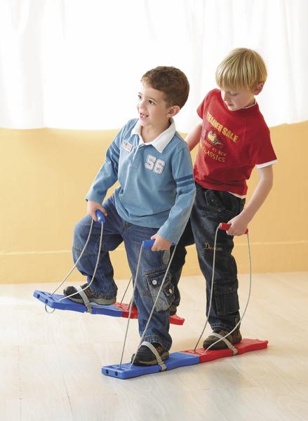 Zwei Jungen spielen gemeinsam mit einem Holzlaufspielzeug in einem hellen Raum.