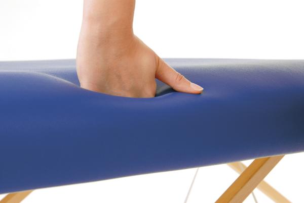 Hand drückt auf weiche blaue Massagebank, zeigt Polsterkomfort und Elastizität.