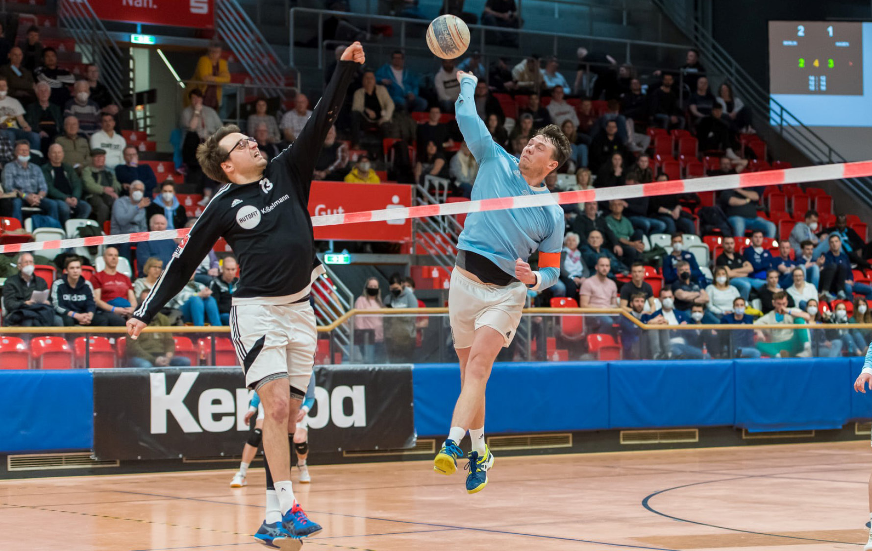 Zwei Faustballspieler schlagen nach dem Ball am Band.