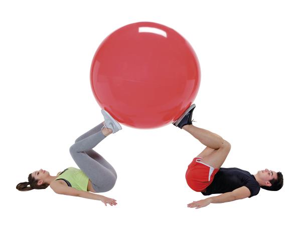 Frau und Mann trainieren gemeinsam mit großem roten Gymnastikball auf weißem Hintergrund.