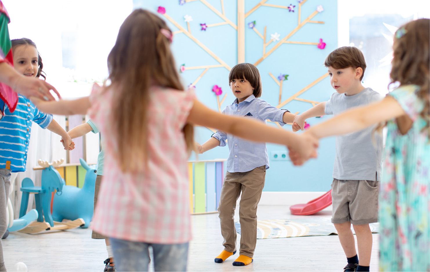 Kindergarten-Kinder stehen im Kreis und halten sich an den Händen fest