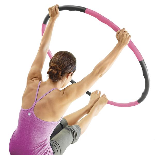 Frau trainiert mit pink-schwarzem Fitnessreifen für Ganzkörper-Workout, Rückenansicht.