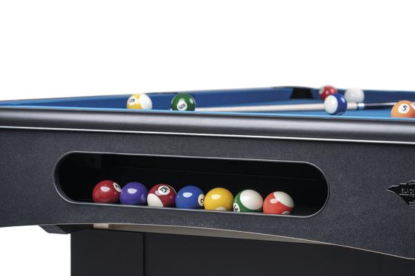 Billardtisch mit bunten Billardkugeln in der Ablage, Nahaufnahme auf schwarzem Tischrahmen.