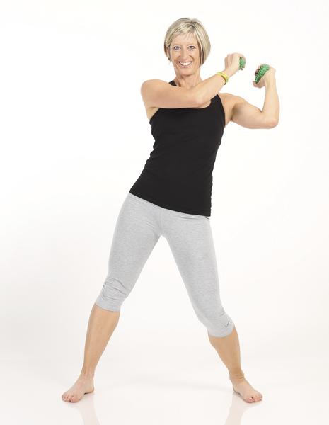 Frau in Sportkleidung macht Fitnessübung mit Handgewichten vor weißem Hintergrund.