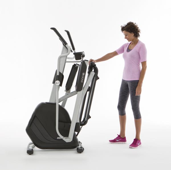 Frau faltet kompaktes Fitnessgerät für Heimtraining, Ellipsentrainer klappbar und platzsparend.
