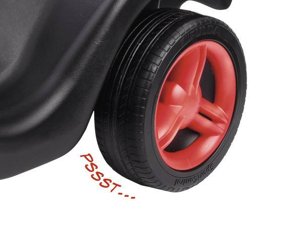 Rotes Kunststoffrad mit schwarzem Reifen an einem Kinderfahrzeug, Nahaufnahme.