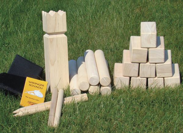 Wikinger Schach Spiel aus Holz mit Kegel, Würfeln und Spielfeld auf grünem Gras.