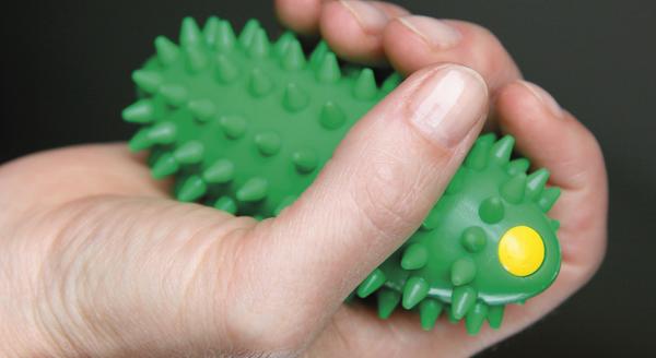 Hand hält grünen, stacheligen Massageball mit gelbem Punkt zur Muskelentspannung.