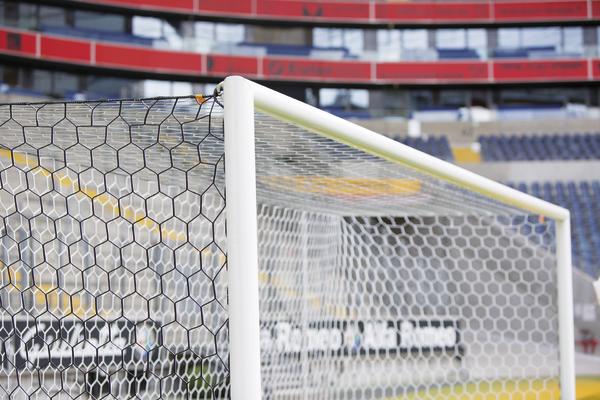 Fußballtor mit Netz im leeren Stadion, Nahaufnahme des Torpfostens und Netzes.
