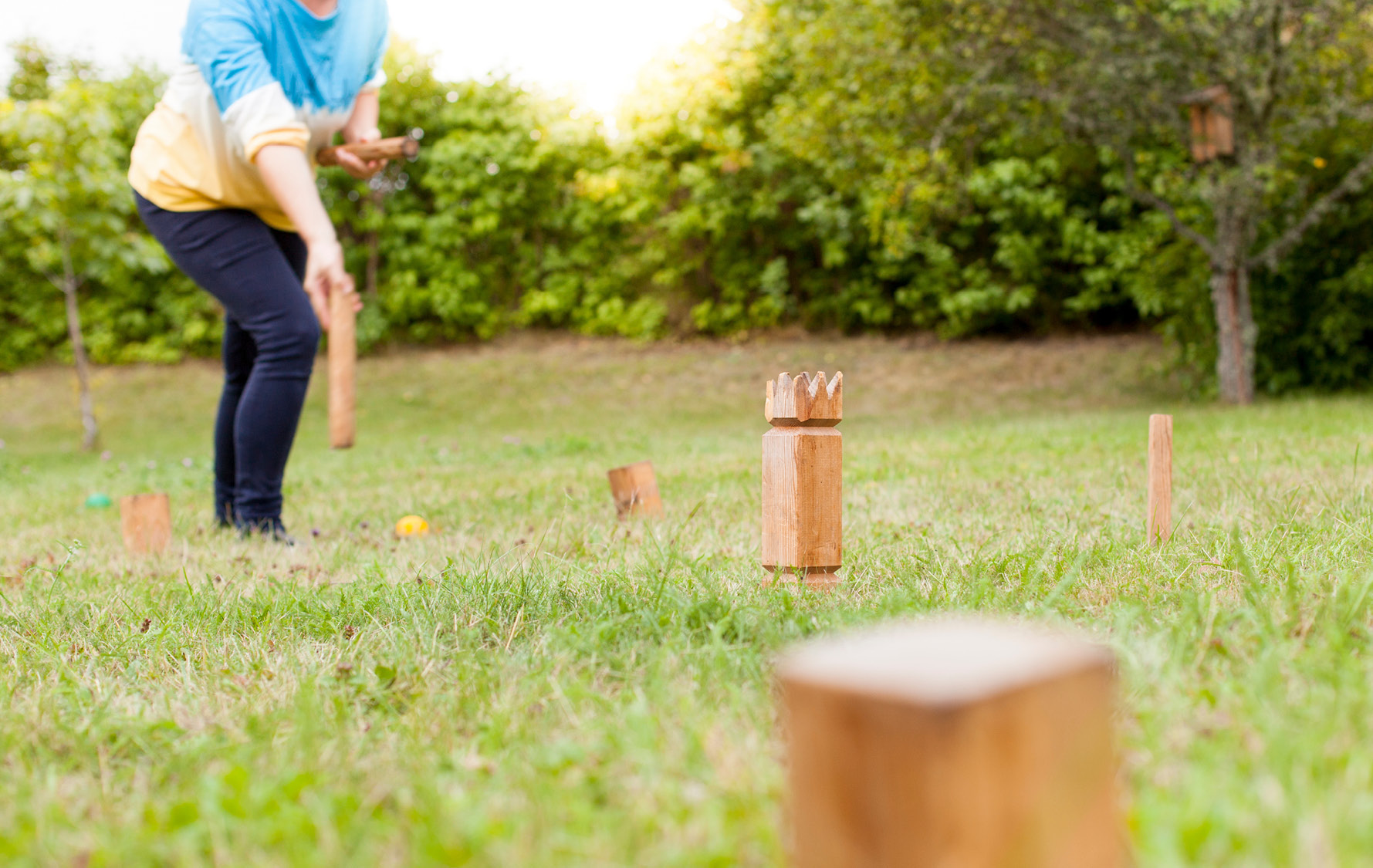 Frau hält Wurfstock für Abwurf auf Kubb in der Hand bereit