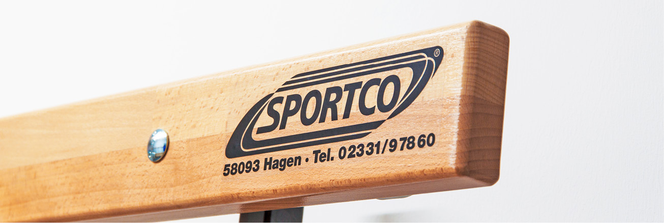 Detailaufnahme einer hochwertigen Umkleidebank aus Holz mit aufgedrucktem SPORTCO-Logo und robuster Verarbeitung.